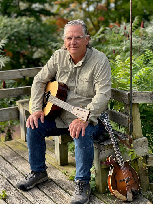 Brent seated with guitar and mandolin